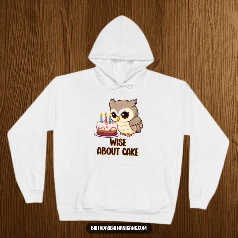 Funny owl hoodie showcasing an inquisitive character intently studying a decorated birthday cake, brimful of wonder.