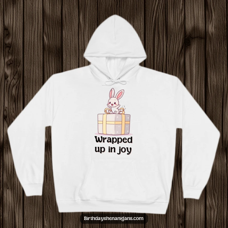 Funny hoodie with a kawaii bunny happily bouncing on a giant present, offering cozy cheer and a delightful funny gift.